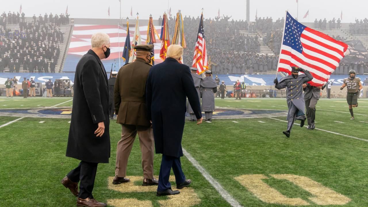 President Donald J. Trump is escorted on to the football field as an Army cadet runs with a U.S. flag Saturday, Dec. 12, 2020, prior the coin toss to the start of the 121st Army-Navy football game at the U.S. Military Academy at West Point, N.Y.